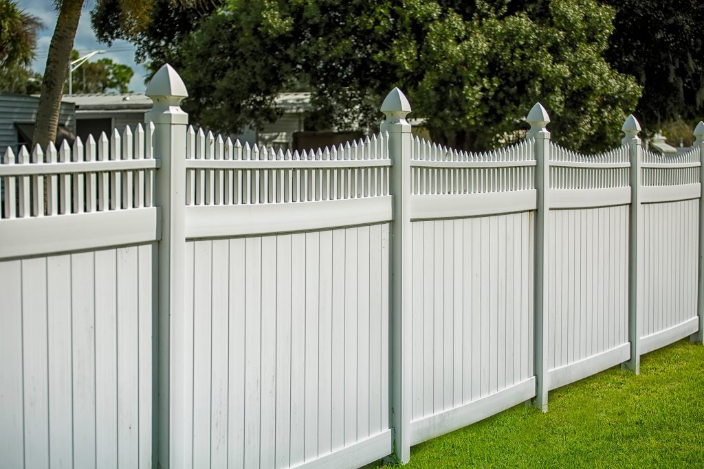 White panel garden fencing with decorative picket top and posts installed along a residential lawn.