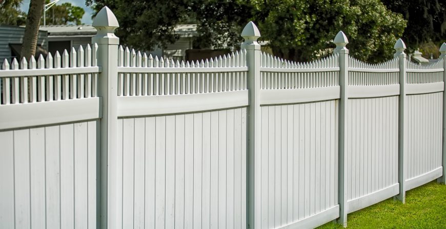 White panel garden fencing with decorative picket top and posts installed along a residential lawn.
